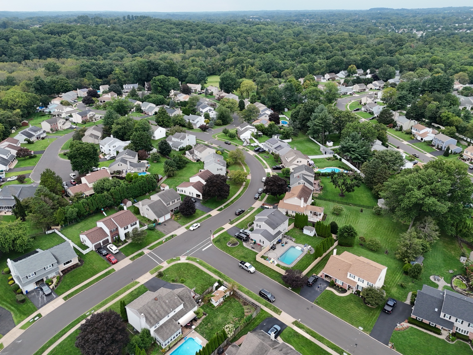 Closer aerial view of homes, yards, and a residential intersection
